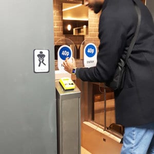 Customer pays with their smart watch to enter a public restroom. Using a contactless wearable watch they no longer need to carry cash or even a credit card.